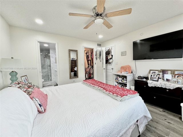 bedroom with a closet, a walk in closet, ensuite bath, light wood-type flooring, and ceiling fan