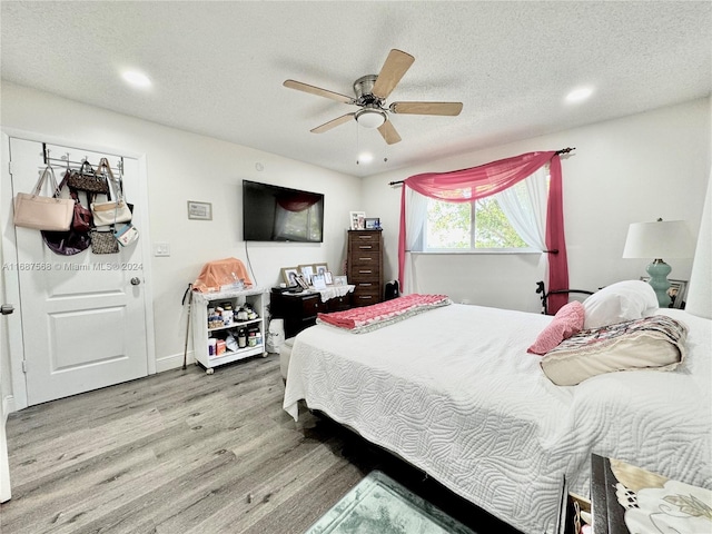 bedroom with ceiling fan, a textured ceiling, and hardwood / wood-style floors