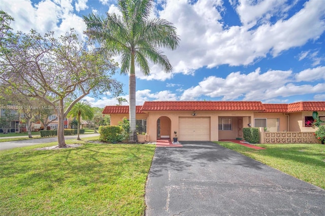 mediterranean / spanish-style home featuring a front lawn and a garage