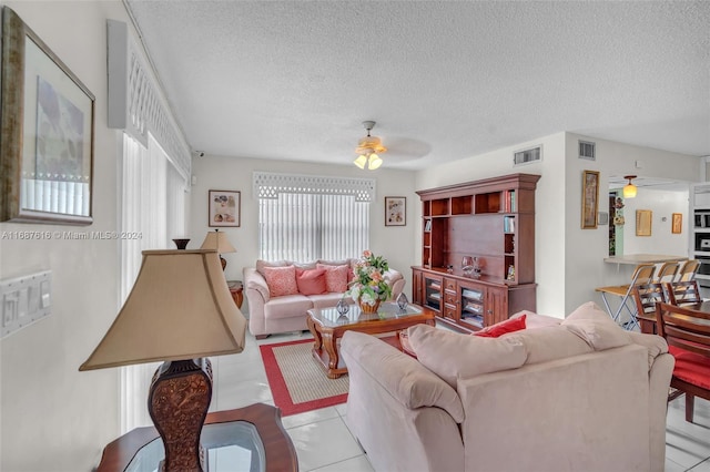 living room with a textured ceiling, ceiling fan, and light tile patterned floors