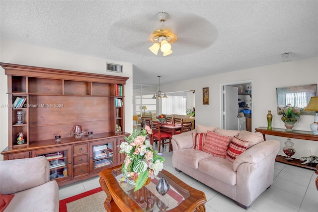 living room featuring a textured ceiling, light tile patterned floors, and ceiling fan