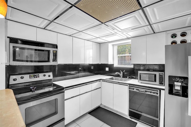 kitchen featuring stainless steel appliances, sink, light tile patterned floors, white cabinets, and decorative backsplash