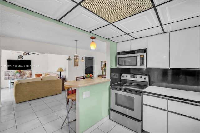 kitchen with white cabinetry, hanging light fixtures, light tile patterned flooring, and stainless steel appliances