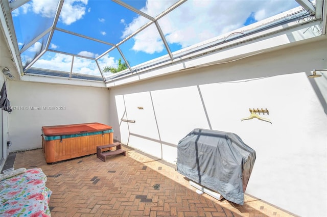 view of patio / terrace featuring a hot tub, glass enclosure, and a grill