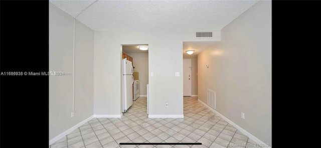 tiled empty room with a textured ceiling