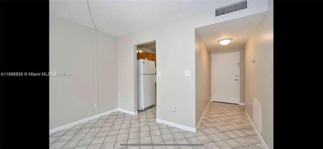 hallway with a textured ceiling and light tile patterned floors