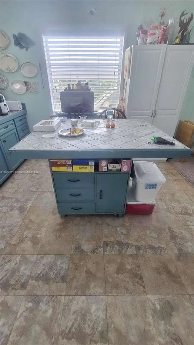 interior space with tile countertops and blue cabinets