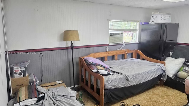 bedroom featuring a wainscoted wall, cooling unit, and freestanding refrigerator
