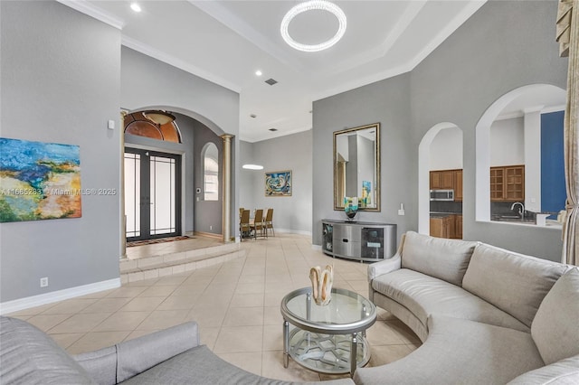 tiled living room with crown molding, decorative columns, french doors, and a high ceiling