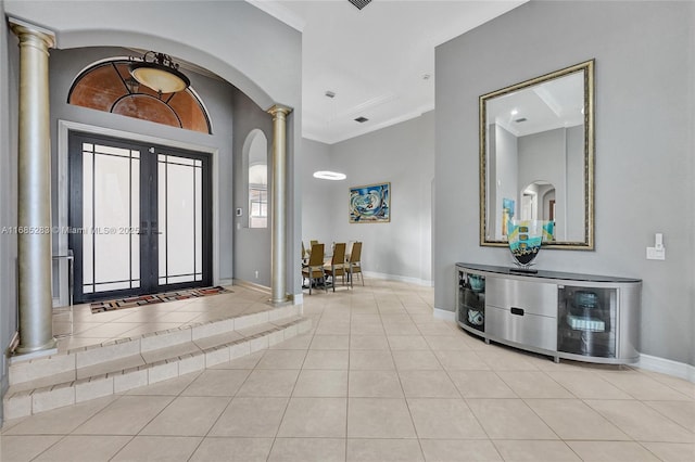 tiled foyer with french doors, ornamental molding, and decorative columns