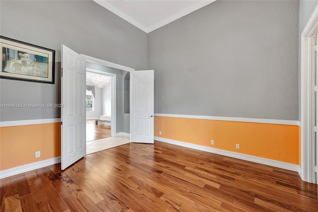 empty room featuring hardwood / wood-style flooring, crown molding, and a notable chandelier