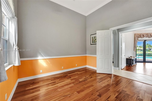 empty room featuring wood-type flooring, vaulted ceiling, and french doors