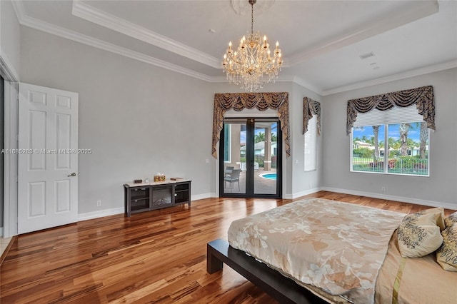 bedroom featuring access to exterior, hardwood / wood-style floors, and a raised ceiling