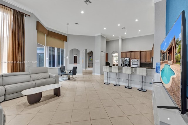 living room featuring crown molding, a high ceiling, and light tile patterned flooring