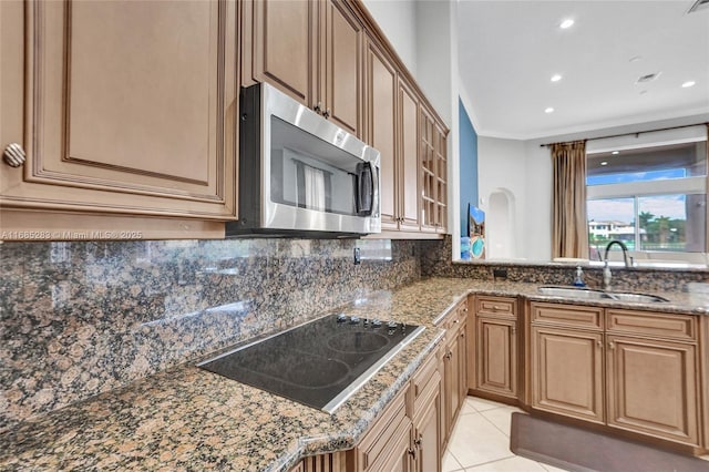 kitchen with dark stone countertops, black electric stovetop, backsplash, and sink