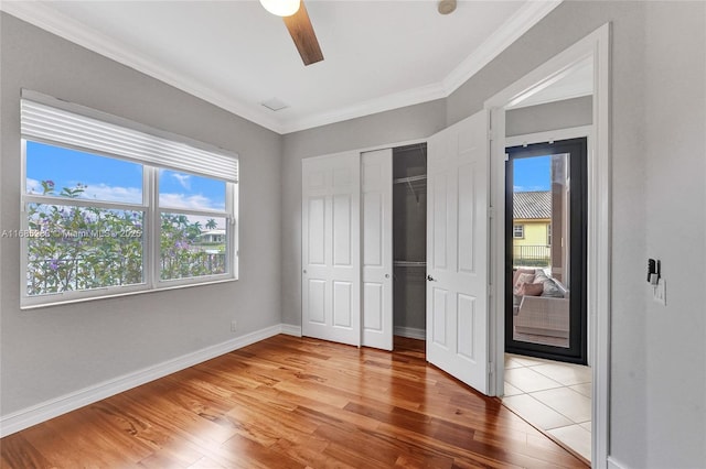 unfurnished bedroom featuring crown molding, hardwood / wood-style flooring, a closet, and ceiling fan