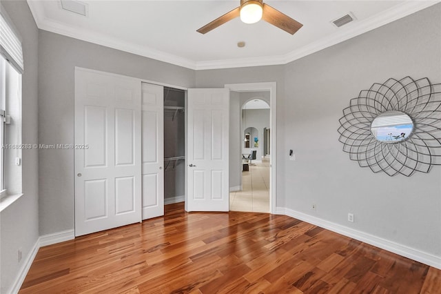 unfurnished bedroom featuring crown molding, hardwood / wood-style floors, ceiling fan, and a closet