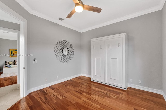 unfurnished bedroom with hardwood / wood-style flooring, ornamental molding, and ceiling fan