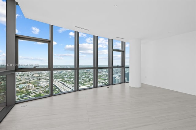 empty room featuring a wall of windows, a water view, and plenty of natural light