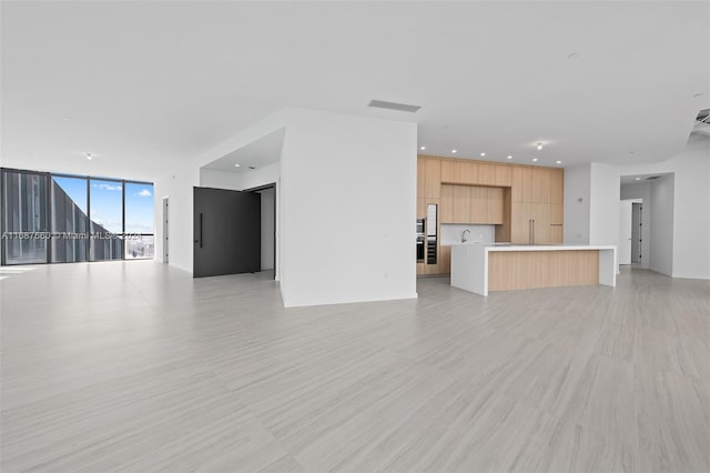 unfurnished living room with light wood-type flooring and a wall of windows