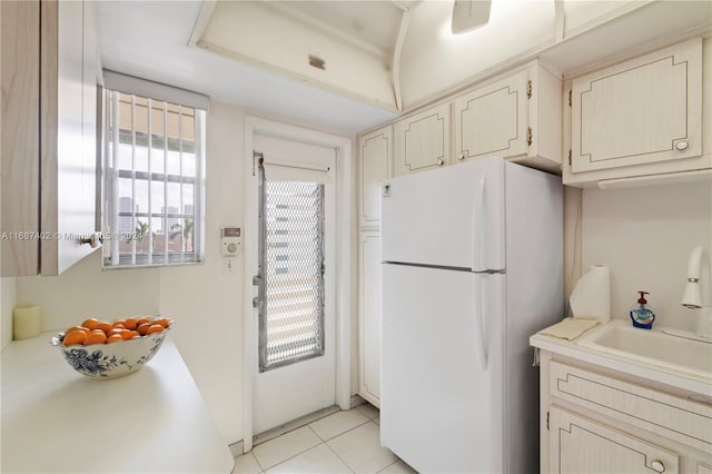 kitchen with white fridge, light tile patterned floors, and sink