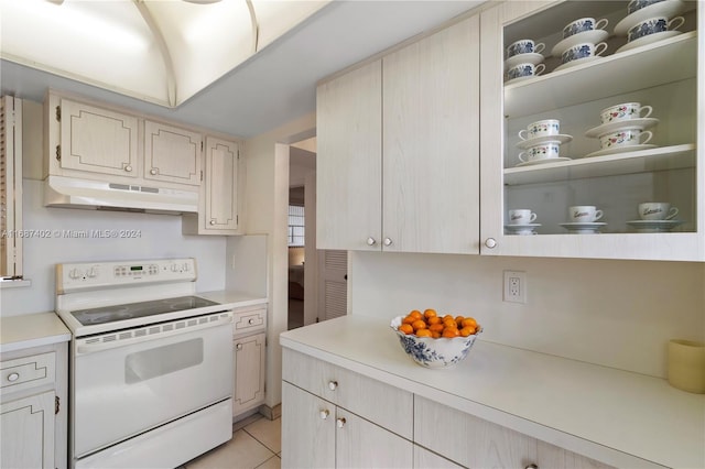 kitchen with light tile patterned floors, light brown cabinets, and white range with electric stovetop