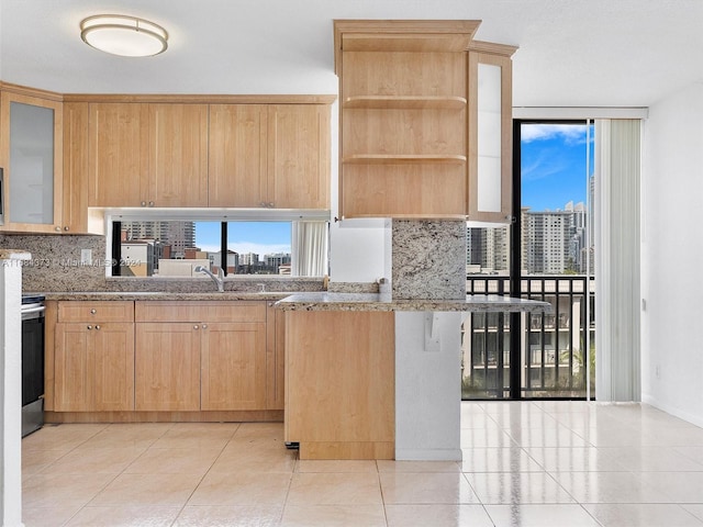 kitchen featuring light tile patterned flooring, decorative backsplash, light stone counters, and light brown cabinetry