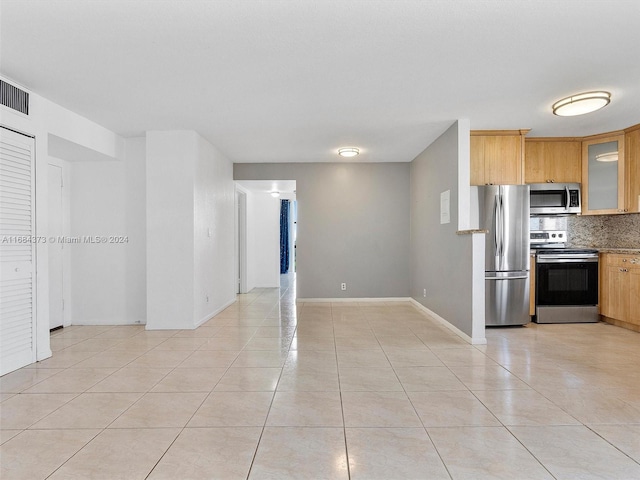 kitchen featuring light brown cabinetry, appliances with stainless steel finishes, backsplash, and light tile patterned flooring