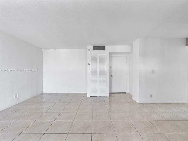 empty room featuring a textured ceiling and light tile patterned floors