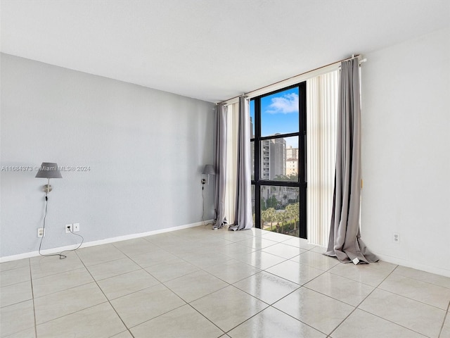 spare room featuring light tile patterned floors and a wall of windows