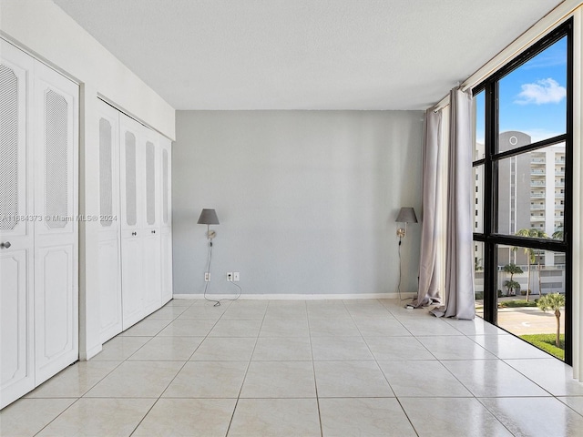 unfurnished bedroom with expansive windows, a textured ceiling, and light tile patterned floors