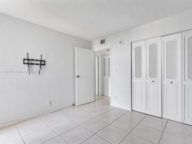 unfurnished bedroom with a closet, a textured ceiling, and light tile patterned floors