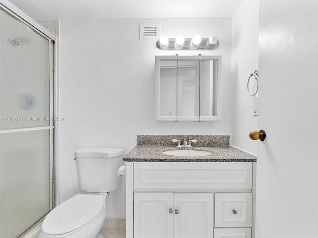 bathroom with vanity, a shower with shower door, and toilet