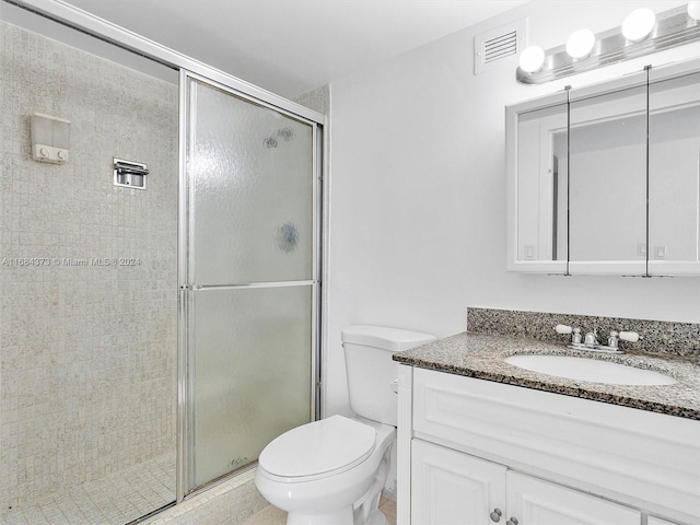 bathroom featuring toilet, a shower with shower door, and vanity