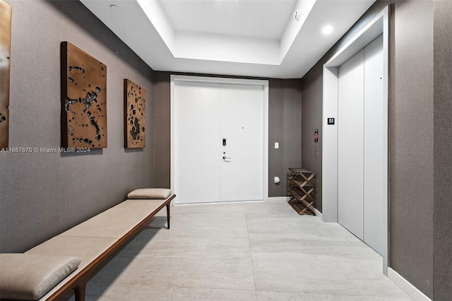 hallway featuring a tray ceiling and elevator