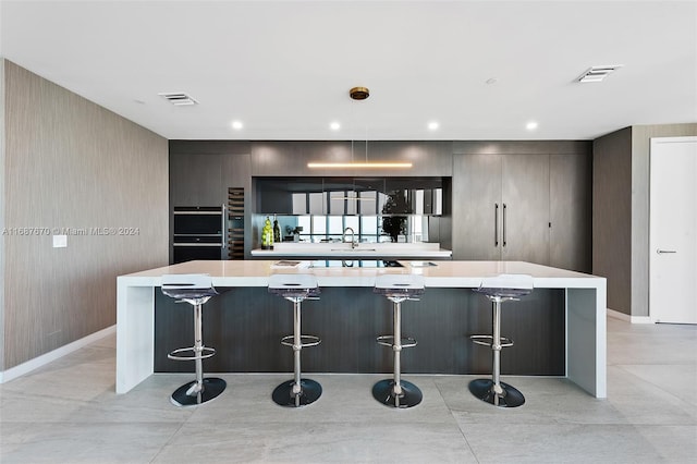 kitchen with a spacious island, a breakfast bar, and black double oven