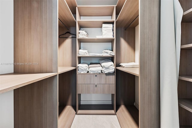 walk in closet with light hardwood / wood-style floors