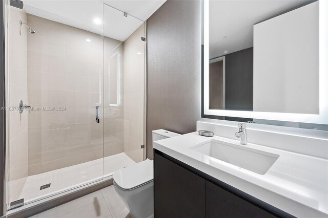 bathroom featuring vanity, toilet, a shower with shower door, and tile patterned flooring