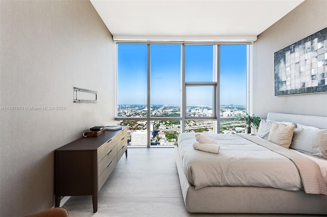 bedroom featuring light hardwood / wood-style floors, multiple windows, and a wall of windows