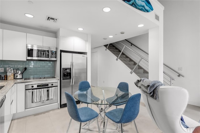 kitchen with backsplash, appliances with stainless steel finishes, white cabinets, and light tile patterned floors