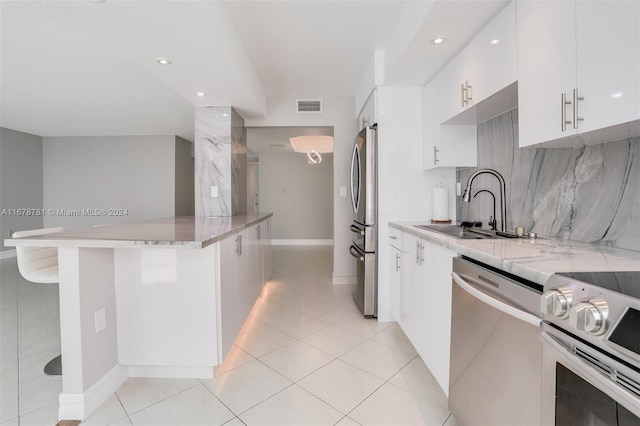 kitchen with a kitchen breakfast bar, sink, kitchen peninsula, white cabinetry, and stainless steel appliances