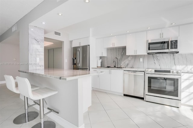 kitchen featuring white cabinets, stainless steel appliances, a breakfast bar area, and sink