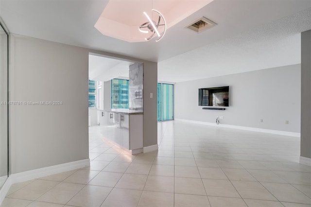 unfurnished room with a textured ceiling, a notable chandelier, and light tile patterned flooring