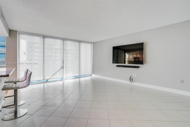 unfurnished living room featuring expansive windows, a wealth of natural light, light tile patterned flooring, and a textured ceiling