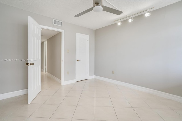 tiled spare room featuring rail lighting, ceiling fan, and a textured ceiling