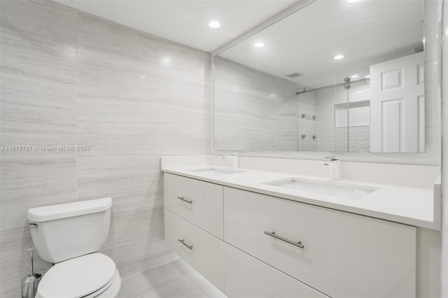 bathroom featuring tile patterned floors, vanity, toilet, and tile walls