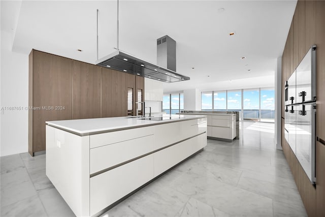 kitchen featuring wood walls, white cabinetry, a spacious island, range hood, and black electric stovetop