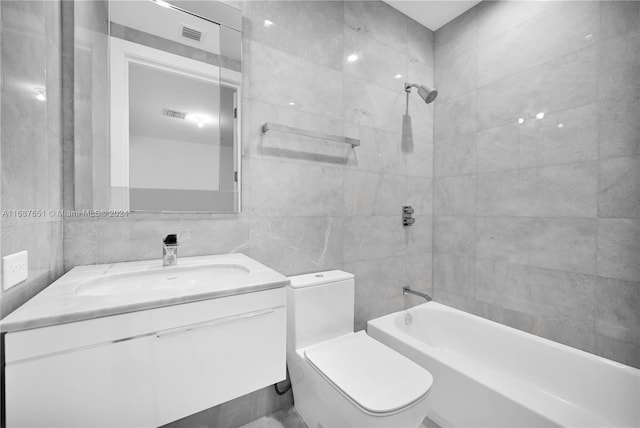 full bathroom featuring tile walls, vanity, tiled shower / bath combo, and toilet