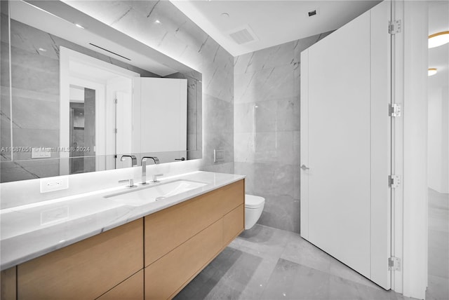 bathroom with toilet, vanity, and tile walls