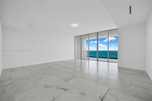 unfurnished room featuring expansive windows and a water view